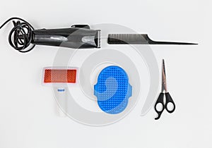 Set for grooming of a dog - hair clipper, scissors, combs on white background. Close up of tools for cats or dogs grooming.