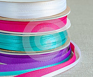 Set of grosgrain ribbons: blue, violet, crimson, white. Background burlap. photo