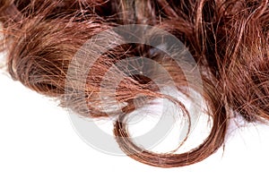 A set of hair extensions of reddish brunette curly hair on a beauty shop table