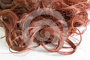 A set of hair extensions of reddish brunette curly hair on a beauty shop table