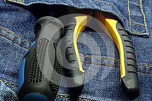 Set of hand tools screwdriver yellow black pliers pocket of jeans close-up background grunge background