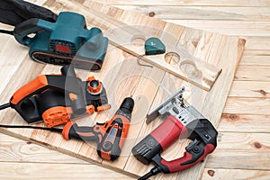 Set of handheld woodworking power tools for woodworking and workpiece lies on a light wooden background