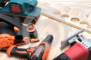 Set of handheld woodworking power tools for woodworking and workpiece lies on a light wooden background. Close up