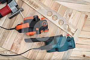 Set of handheld woodworking power tools for woodworking and the workpiece lies on a light wooden background. Directly above