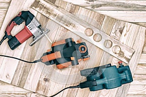 Set of handheld woodworking power tools for woodworking and the workpiece lies on a light wooden background. Directly above