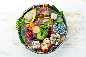 Set of healthy food in a wooden box: vegetables, fruits, fish, meat, nuts and herbs.