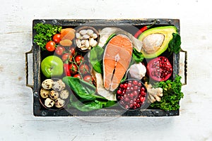 Set of healthy food in a wooden box: vegetables, fruits, fish, meat, nuts and herbs.