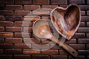 Set of heartshaped wood bowl and spoon on wooden backcloth