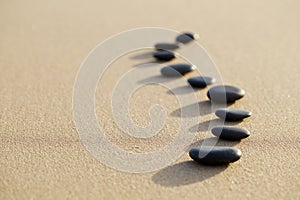 set of hot stone on white sand calm beach in backbone shape. selective focus, spa concept