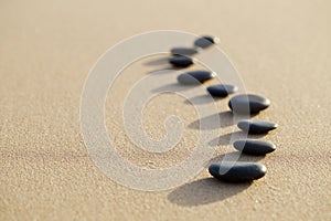 set of hot stone on white sand calm beach in backbone shape. selective focus, spa concept photo