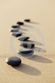 set of hot stone on white sand calm beach in backbone shape. selective focus, spa concept