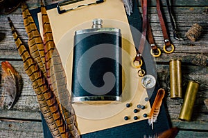 Set of hunting equipment on vintage desk. Hunting belt with cartridges, and clipboard with paper on wooden background