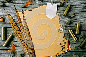 Set of hunting equipment on vintage desk. Hunting belt with cartridges, and clipboard with paper on wooden background