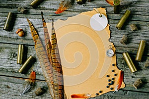 Set of hunting equipment on vintage desk. Hunting belt with cartridges, and clipboard with paper on wooden background