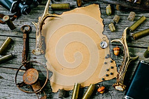 Set of hunting equipment on vintage desk. Hunting belt with cartridges, and clipboard with paper on wooden background