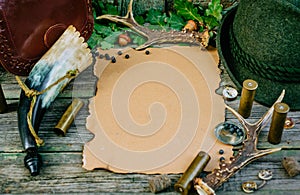 Set of hunting equipment on vintage desk. Hunting belt with cartridges, and clipboard with paper on wooden background