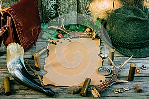 Set of hunting equipment on vintage desk. Hunting belt with cartridges, and clipboard with paper on wooden background