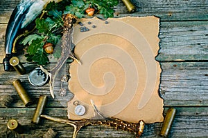 Set of hunting equipment on vintage desk. Hunting belt with cartridges, and clipboard with paper on wooden background