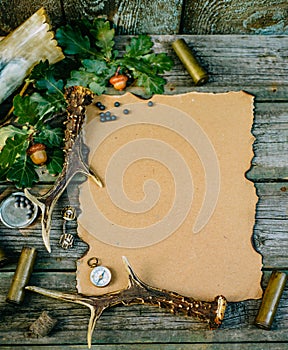 Set of hunting equipment on vintage desk. Hunting belt with cartridges, and clipboard with paper on wooden background