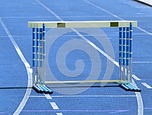 Set of hurdles or obctacles ready on blue race track at starting line