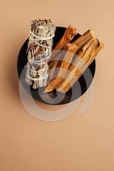 Set of incense for fumigation. White sage sprigs and Palo Santo sticks tied in bunch in metal bowl.