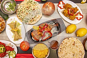 Set of Indian food dishes with hands dipping the chicken tikka masala,