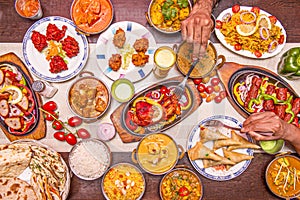 Set of Indian food dishes with hands poking the chicken tikka masala