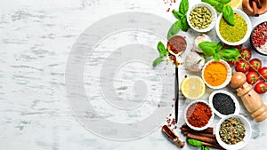 Set of Indian spices, basil and herbs on a white wooden background.