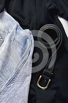 a set of jeans trousers, black shirts and a leather belt close-up. online shopping concept.