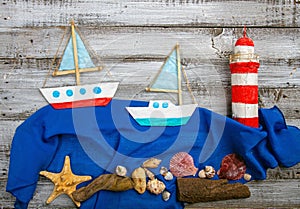 set of kids handcrafted boats, fish, nautical attributes and more on rough vintage wooden background top view