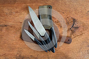 Set of kitchen knifes on wooden cutting board on wooden tabl