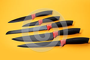 Set kitchen knives with a black handle on yellow background