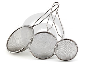 Set of kitchen strainers of different sizes on a white background. The smallest tea strainer and the largest for rice or pasta