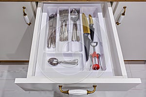 Set of knives, forks and  spoons on the shelf in the kitchen cabinet