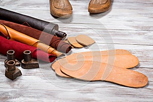 Un conjunto compuesto por piel en rollos de pan vasos herramientas en blanco de madera. lugar de trabajo zapatero. en negocios mano herramientas sobre el mesa 