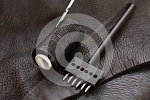 Set of leather work tools on black leather. Workplace for shoemaker