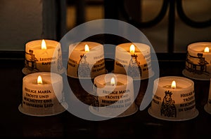 Set of lit church candles in a line with the illustration of the Virgin Mary and baby Jesus