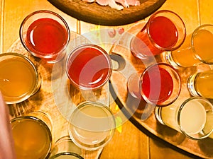 A set of lots of delicious yellow orange red glasses, shots with strong alcohol, vodka, filling, brandy on wooden stands