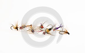 Set of lures flies for fly fishing on a uniform white background close-up front view. Elements of fishing equipment or tackle for
