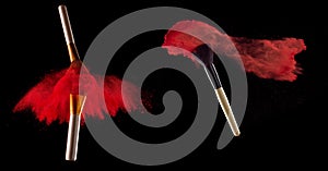 Set of makeup brush with red powder explosion on black background