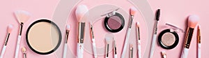 Set of makeup brushes and facial cosmetics isolated on pink background. Fashion make-up beauty products, wide banner