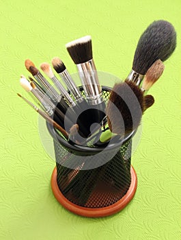 A set of makeup brushes on a light green background