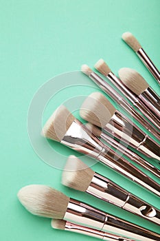 Set of makeup brushes on mint background. Top view. Space for text