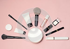 Set of makeup cosmetics, brushes, concealer and other essentials on pink background