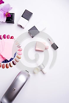 Set for manicure with gell polish  bottles, LED lamp and accessoires on white background. flat lay photo