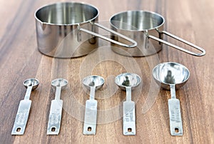 Set of measuring cups and measuring spoons use in cooking lay on dark brown table