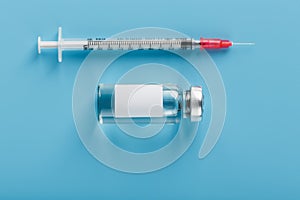 Ampoule with a vaccine and a syringe for viruses and diseases on a blue background photo