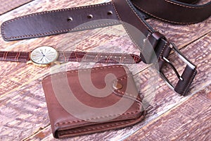 Set of men`s accessories for the business with leather belt, wallet, watch and smoking pipe on a wooden background. The