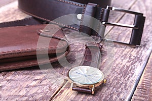 Set of men`s accessories for the business with leather belt, wallet, watch and smoking pipe on a wooden background. The