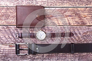 Set of men`s accessories for the business with leather belt, wallet, watch and smoking pipe on a wooden background. The